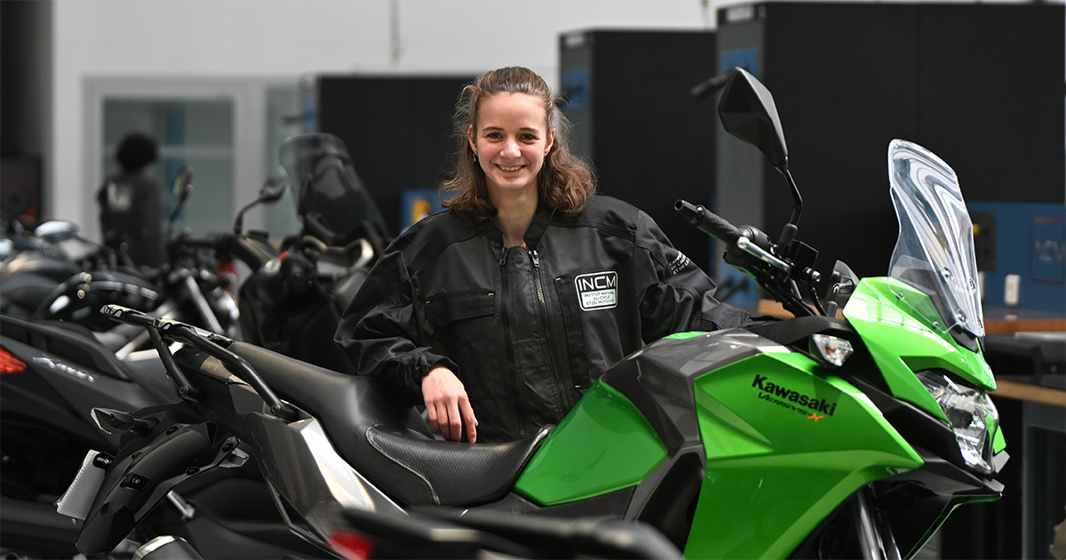 Portrait de Zoé Osmont debout derrière une moto verte Kawazaki