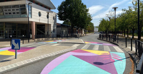 oeuvre d'art colorée au sol devant une école autour d'un passage piéton