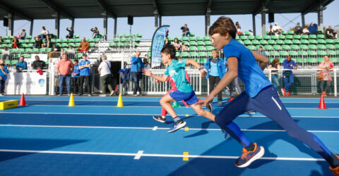 enfants qui courent sur une piste d’athlétisme bleue.