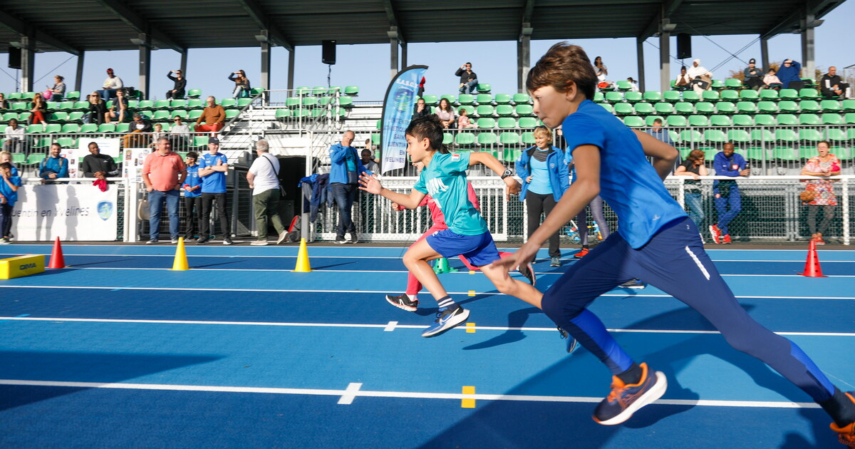 enfants qui courent sur une piste d’athlétisme bleue.
