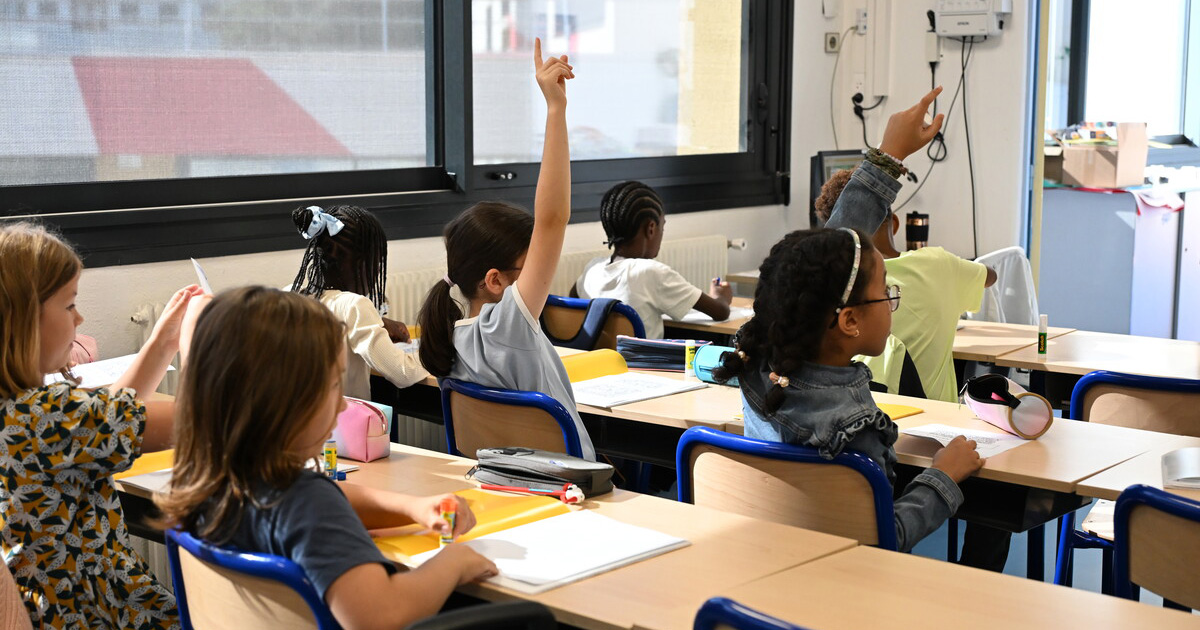 classe avec élèves qui lèvent la main pour répondre à la maitresse